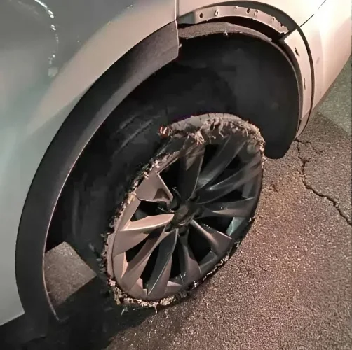 Rear wheel of a Tesla with the tire blown out to the rim, sidewall shredded to frayed cords