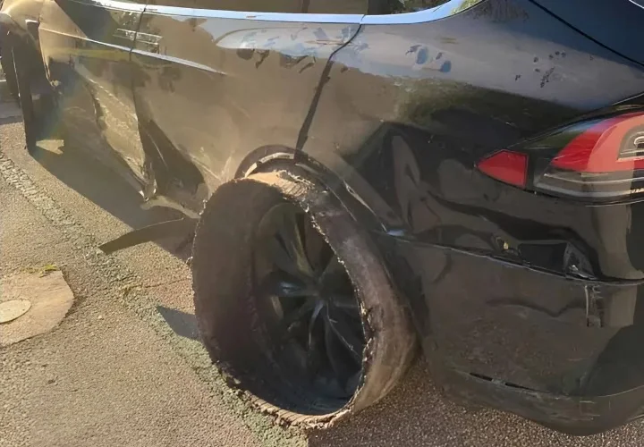 Tesla Model X with the rear tread separated from the tire and body damage along the side